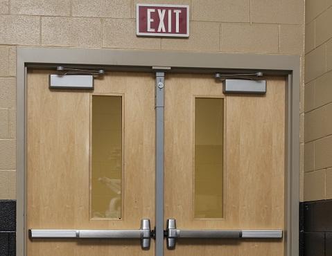 Commercial exit doors with panic bars, closers, and illuminated exit signage
